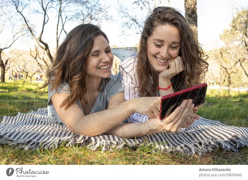 ein paar Mädchen, die auf einer Decke in einem Park liegen, nehmen sich mit dem Handy Erwachsener attraktiv schön Schönheit Fotokamera Funktelefon heiter