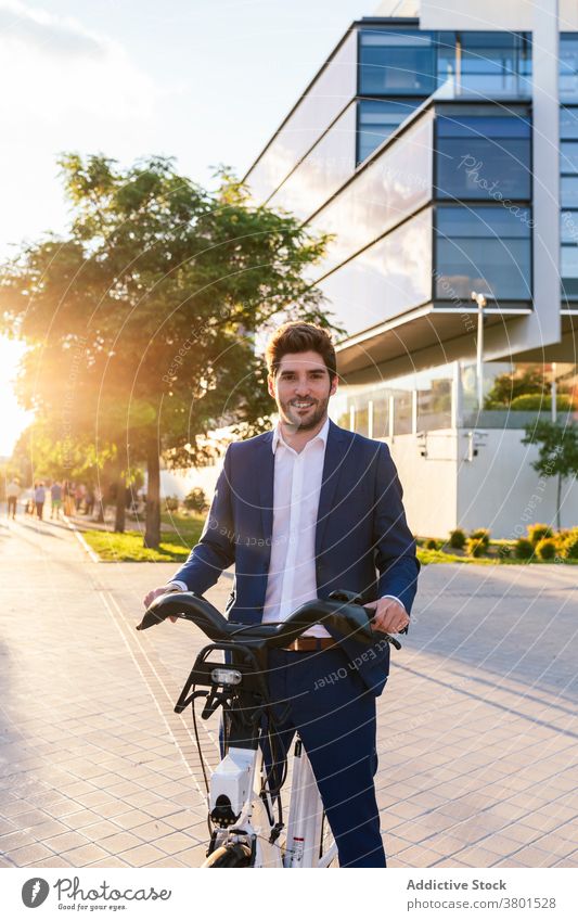 Stilvoller Mann im Anzug zu Fuß auf dem Bürgersteig mit Elektrofahrrad stylisch Bekleidung Mode elektrisch Fahrrad Spaziergang Arbeitsweg Straße maskulin formal