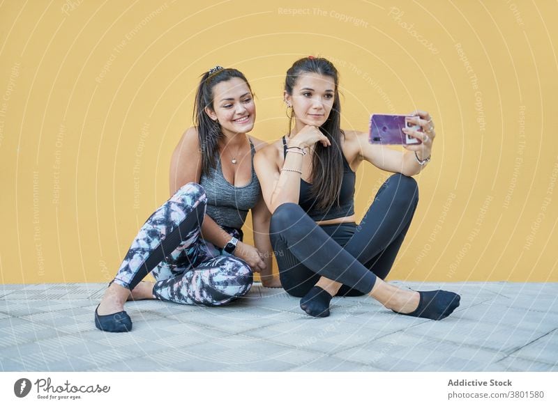 Positive Frauen sitzen auf dem Boden und nehmen Selfie auf Smartphone Inhalt positiv Apparatur Freund heiter benutzend Moment Stock modern jung Mobile Telefon