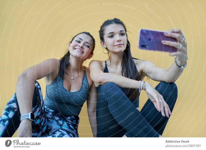 Positive Frauen sitzen auf dem Boden und nehmen Selfie auf Smartphone Inhalt positiv Apparatur Freund heiter benutzend Moment Stock modern jung Mobile Telefon