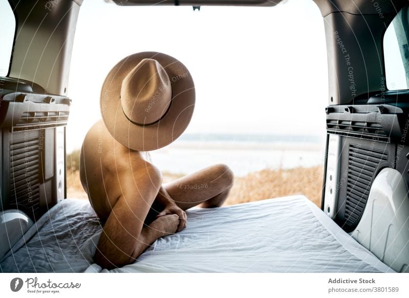Unerkennbarer nackter Mann mit Hut, der auf einer Matratze in einem Fahrzeug ruht Tourist nachdenken Meer Schlafmatratze Urlaub Himmel Horizont endlos Filz