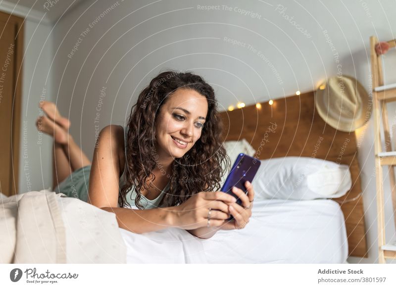 Fröhliche Frau Surfen Smartphone im Bett am Morgen Browsen Schlafzimmer benutzend wach sorgenfrei Pyjama Lügen weich Komfort heimwärts Apparatur Gerät