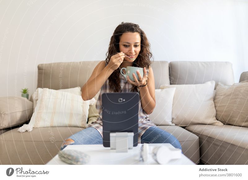 Frau trinkt Kaffee und verwendet Tablette zu Hause Frühstück Morgen sich[Akk] entspannen Wochenende zuschauen Film unterhalten heimwärts Outfit Sofa Tasse