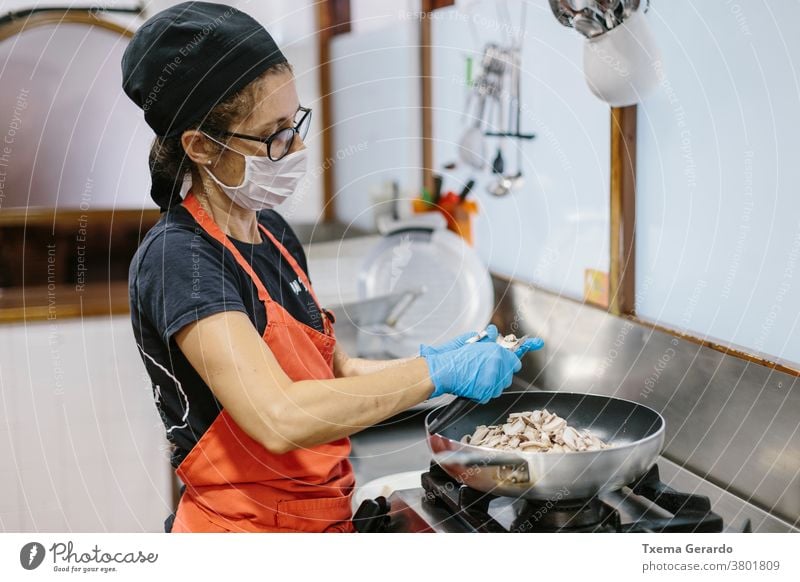Ein Koch in einem Restaurant, der eine Maske trägt, als Vorsichtsmaßnahme gegen das Coronavirus, das die Mahlzeit zubereitet. Küche Mundschutz covid-19