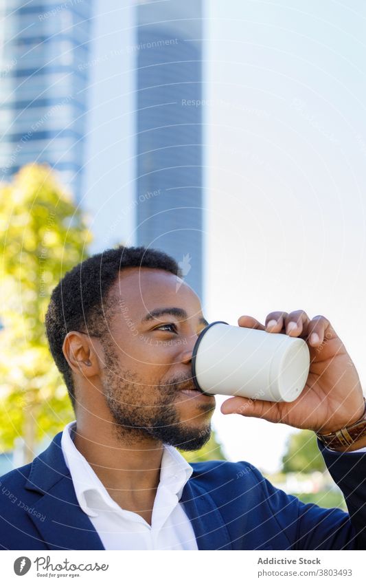 Bärtiger junger schwarzer Geschäftsmann trinkt Kaffee in der Innenstadt Mann trinken Straße positiv selbstbewusst Stil Getränk Kaffeepause Stadtzentrum