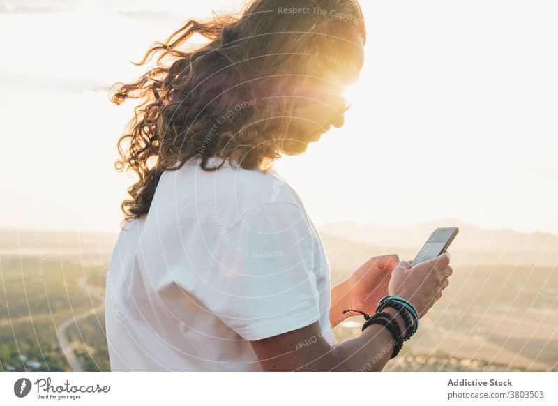 Crop positiv Mann mit Smartphone gegen geräumige grüne Tal benutzend malerisch Windstille Aussichtspunkt Natur Apparatur Bergkuppe Fernweh reisen erstaunlich