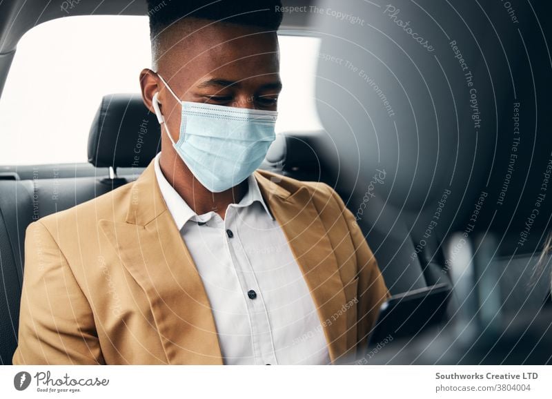 Junger Geschäftsmann mit Maske trägt während Gesundheitspandemie Mobiltelefon auf dem Rücksitz eines Taxis Business Gesichtsmaske Gesichtsbedeckung tragend ppe