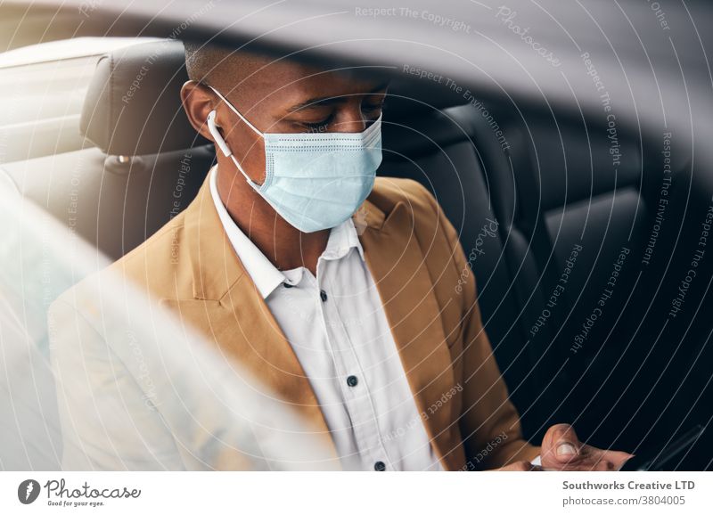 Junger Geschäftsmann mit Maske trägt während Gesundheitspandemie Mobiltelefon auf dem Rücksitz eines Taxis Business Gesichtsmaske Gesichtsbedeckung tragend ppe