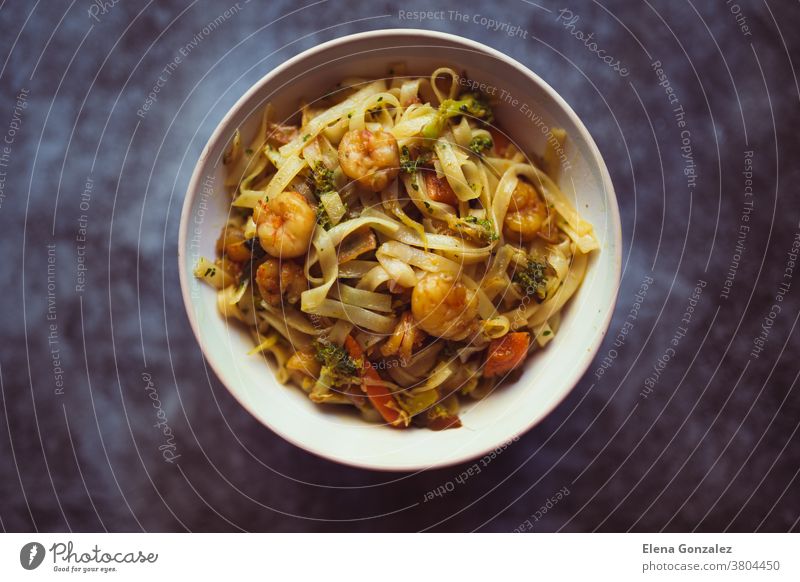 Nudelschüssel mit Gemüse und Garnelen auf dunklem Hintergrund. Asiatisches Essenskonzept. Ansicht von oben Nudeln Schalen & Schüsseln Chinesisch Zwiebel Spätzle