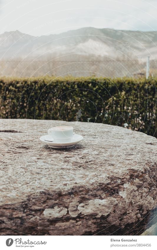 Morgendliche Tasse Kaffee auf einem alten Steintisch mit Berghintergrund bei Sonnenaufgang heiß Café weiß Verdunstung Landschaft Becher Nahaufnahme Hintergrund