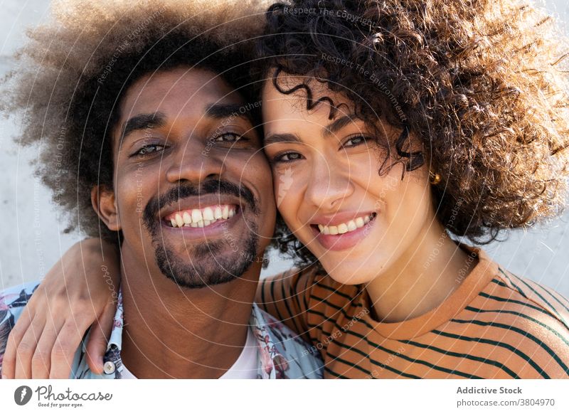 Glückliches junges ethnisches Paar, das sich umarmt und in die Kamera lächelt Lächeln kuscheln heiter Liebe Partnerschaft Zusammensein Umarmen Porträt genießen