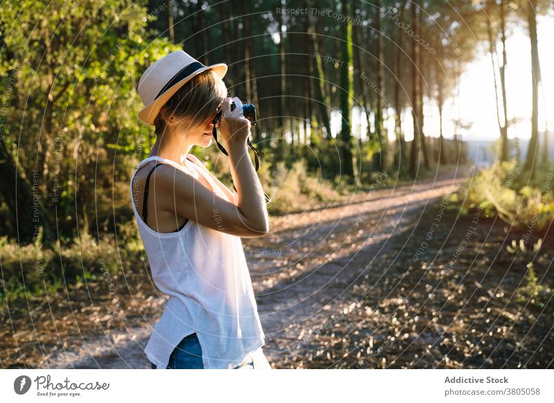 Anonyme junge Frau fotografiert die Natur im Wald fotografieren bewundern Fernweh reisen Fotograf Urlaub Ausflug Sommer schießen lässig Hut Weg Hobby Abenteuer