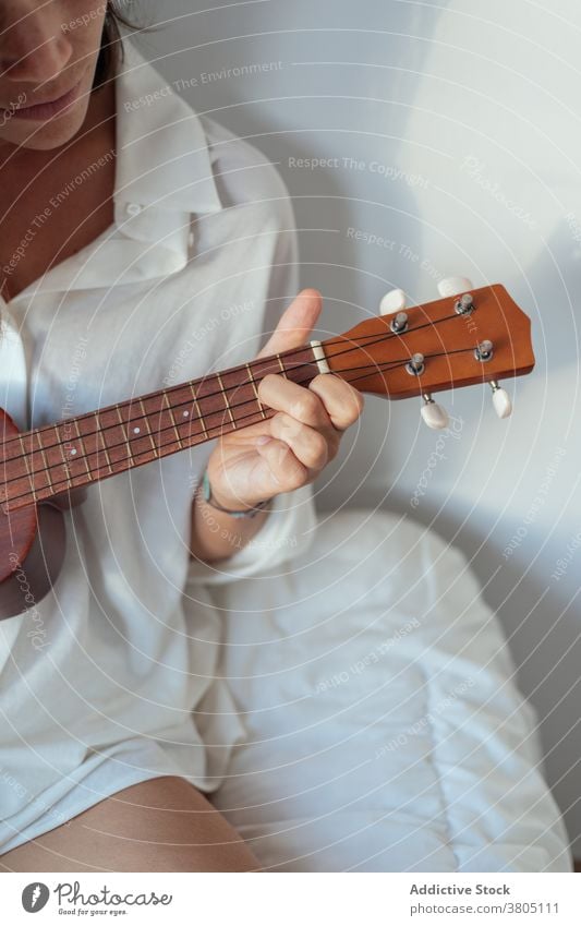Anonyme Frau legt Ukulele auf Bett spielen Verlockung sinnlich Musiker Gesang ausführen ruhen Komfort Morgen jung traumhaft weißes Hemd Melodie genießen