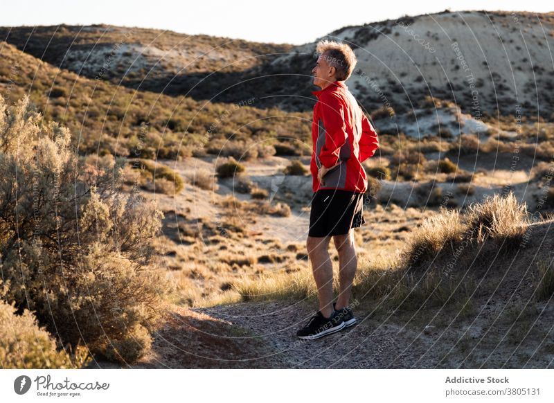 Sportler rastet auf sandigem Untergrund in bergigem Gelände Mann laufen Halbwüste Hügel Training aktiv aussruhen Gesundheit Natur Wohlbefinden Sand Übung