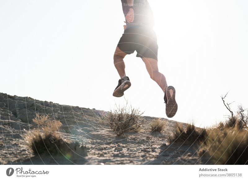 Unerkennbarer Mann läuft in Halbwüstengebiet an sonnigem Tag laufen springen Natur Training Energie Sand aktiv Gelände Läufer männlich Sportbekleidung Wellness