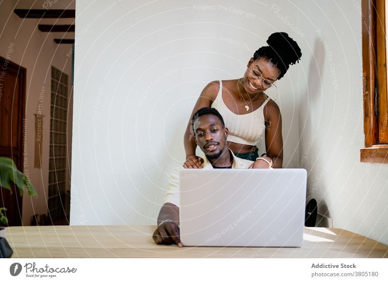 Glückliche schwarze Frau umarmt männlichen Arbeitgeber Paar kuscheln Laptop Erfrischung Appartement Pause freiberuflich Freizeit Partnerschaft Afroamerikaner