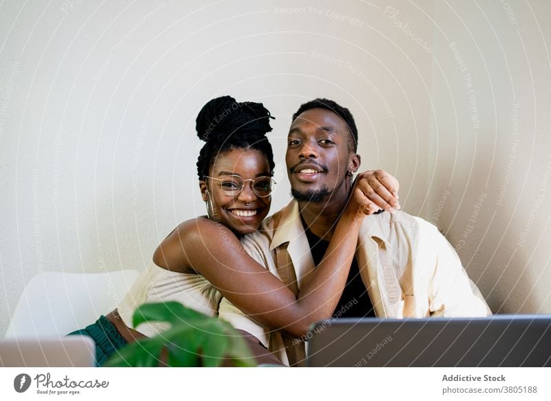 Fröhliche schwarze Freiberufler, die sich in der Pause umarmen Paar Partnerschaft Umarmen zu Hause Laptop Umarmung kuscheln positiv Glück sich[Akk] entspannen