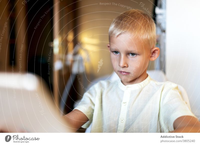 Konzentrierter Junge schaut Filme auf Tablet Tablette Browsen Kind klug Freizeit ernst Konzentration online blond Internet Apparatur Gerät Surfen Anschluss