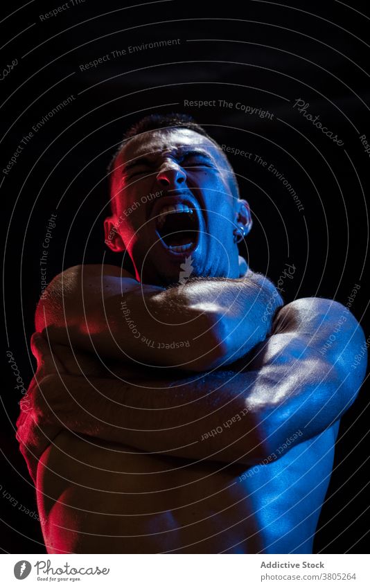 Mann schreit, während er Brust und Hals mit verschränkten Armen bedeckt Schrei schreien Verzweiflung Depression unglücklich Stress Problematik weinen Ärger