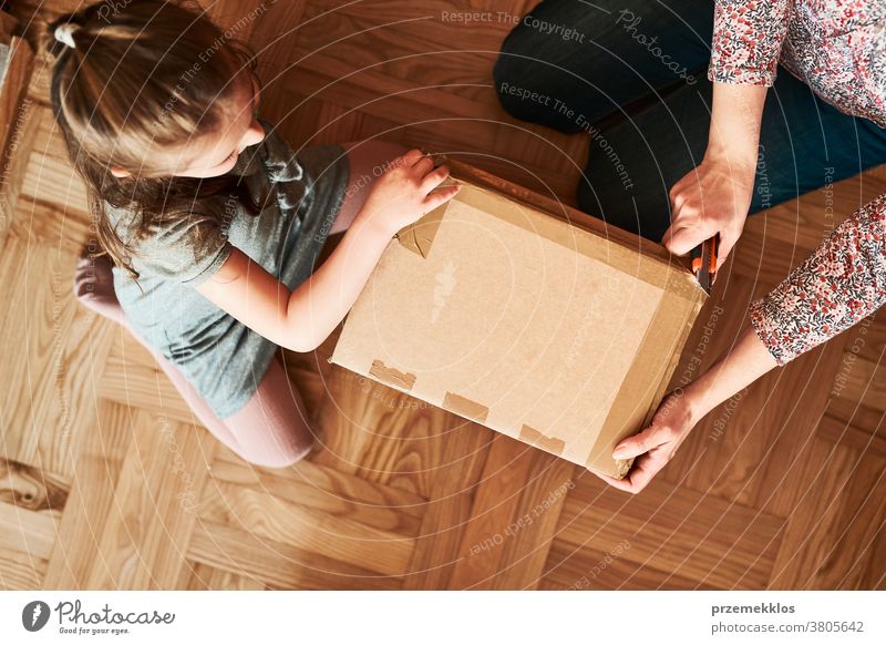 Frau packt mit Hilfe ihrer Tochter ein Pappkarton-Paket aus Ansicht Stock Geschenk Auspacken Klebeband Mädchen Füller schäumen Rudel Top offen Kasten auspacken