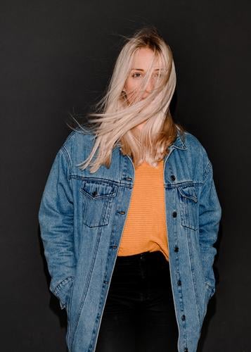 Mode-Portraits einer jungen Frau blond flashlook jeansjacke Paparazzi-Look trashig Modus Pullover Jacke lange haare hübsch Wind wehen Porträt schön Lifestyle
