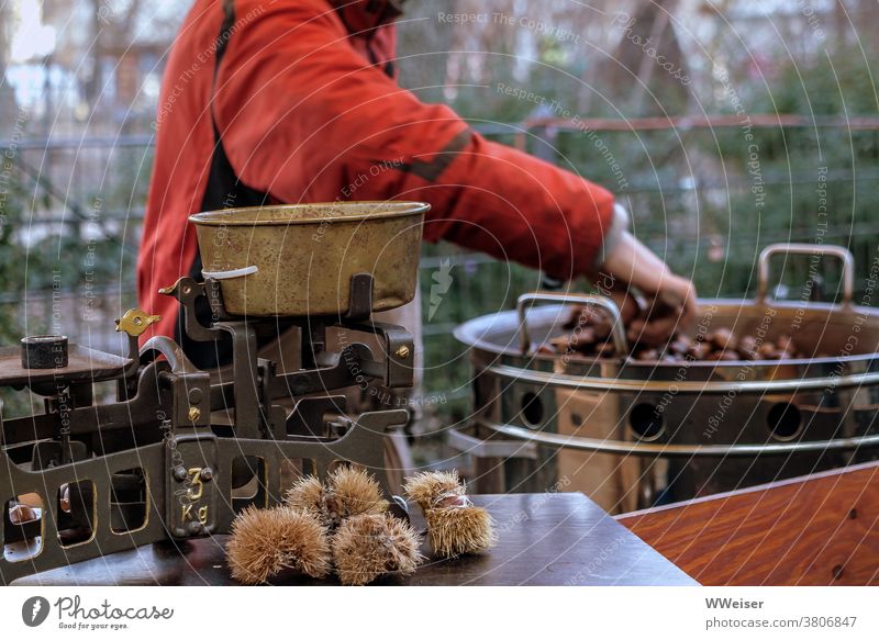 Auf dem Markt sind geröstete Maronen an kalten Tagen besonders beliebt Kastanien Esskastanien marktstand rösten braten backen heiß essen lecker Waage Topf