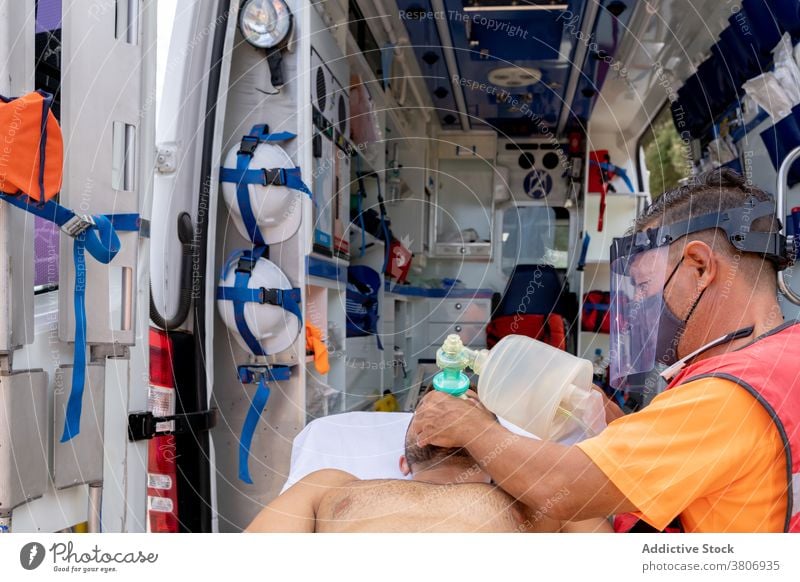 Unerkennbarer Rettungsschwimmer mit Visier, der einem Patienten eine Sauerstoffmaske aufsetzt Mundschutz geduldig Hilfsbereitschaft medizinisch Unterstützung