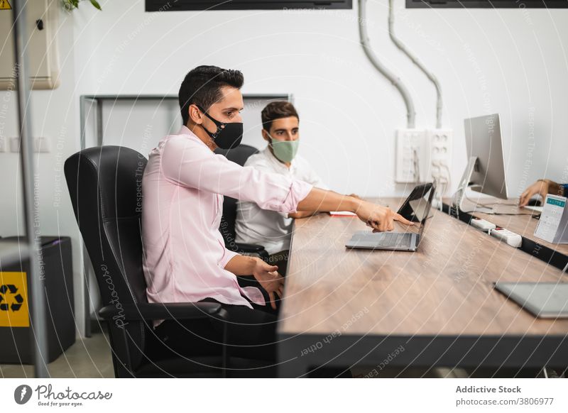 Nicht erkennbare Kollegen mit Masken, die am Laptop bei der Arbeit arbeiten Unternehmer teilen Brainstorming Inbetriebnahme Mundschutz Internet Büro benutzend