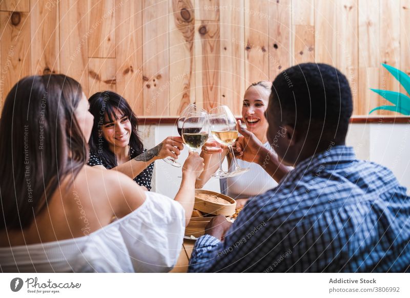 Glücklich diverse Freunde stoßen Gläser im Cafe an Klirren Zuprosten jubelt trinken Wein dine Kantine Abendessen heiter feiern positiv geschmackvoll