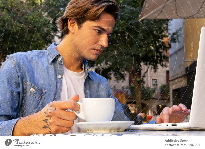 Anonymer Mann benutzt Laptop im Café Kaffee freiberuflich abgelegen trinken Arbeit benutzend beschäftigt männlich Tasse Cappuccino Apparatur Gerät Getränk