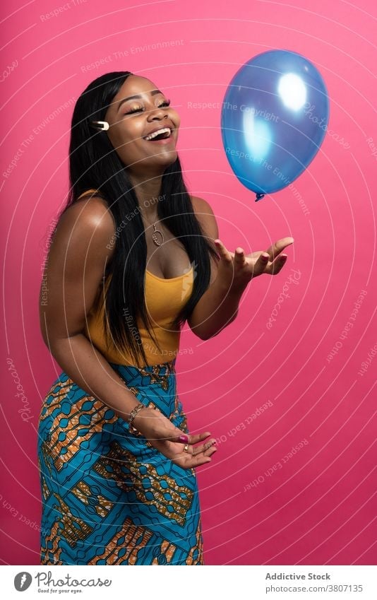 Fröhliche junge afroamerikanische Frau spielt mit Luftballon im Studio spielen Glück heiter Freude Stil Model Lächeln spielerisch positiv Optimist ethnisch