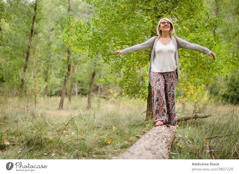 Glückliche Frau steht auf Baumstamm im Wald Gleichgewicht Kofferraum Sommer Freiheit reisen Natur grün erkunden pflanzlich Grün Laubwerk Abenteuer Urlaub