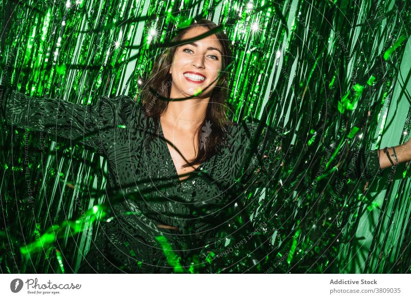 Fröhliche Frau spielt mit grünem Lametta Party Streifen Spaß haben spielerisch Folie Farbe pulsierend glänzend Kleid festlich Glück heiter Freude genießen