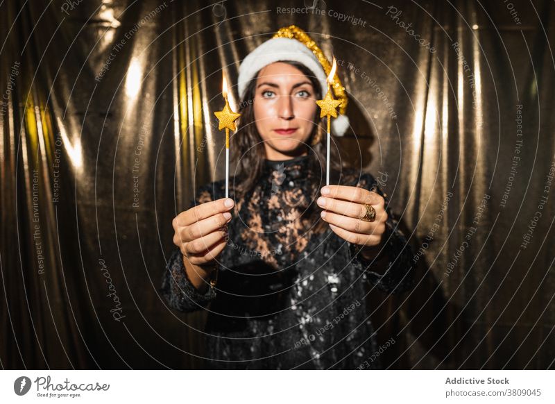 Charmante Frau mit Kerzen auf Party Neujahr feiern Glamour golden Farbe Brandwunde Flamme ausgefallen Kleid Weihnachtsmütze Windstille Hut Tradition Feiertag