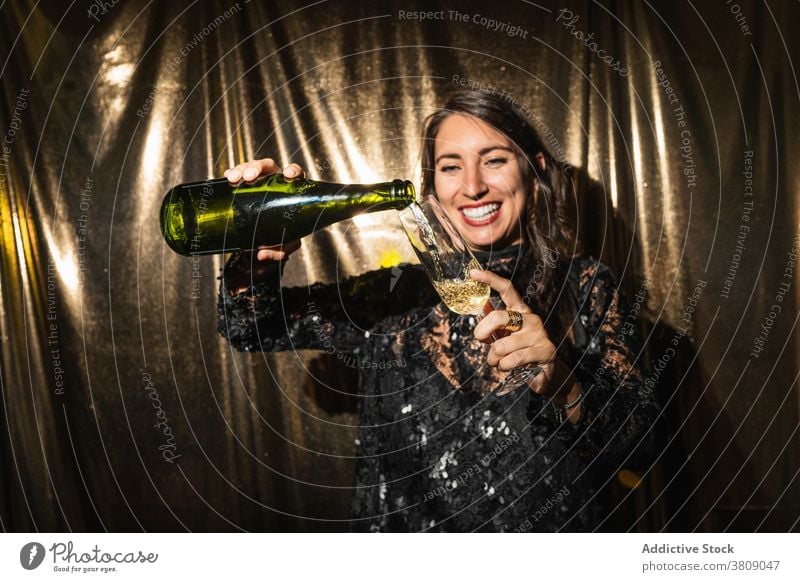 Positive Frau gießt Champagner in Glas Party eingießen Flasche genießen heiter Glamour golden glänzend Kleid Getränk Feiertag trinken funkeln Spaß Freude Stil