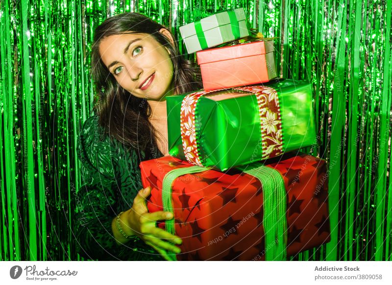 Lächelnde Frau mit Stapel von Geschenken auf der Weihnachtsfeier Weihnachten präsentieren Lametta grün Farbe Kasten Folie glänzend Glamour froh Haufen Kleid