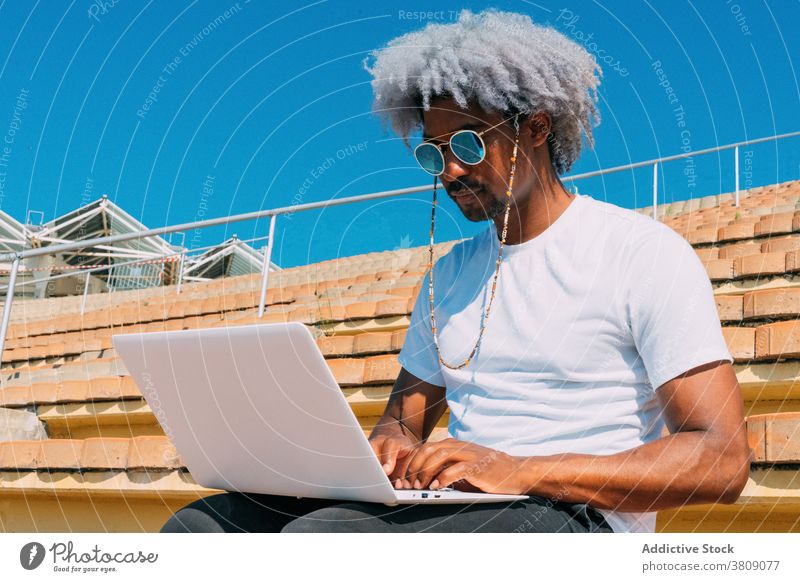 Afro und schwarzer Mann mit Sonnenbrille arbeiten mit seinem Laptop auf th Schwarzer Mann Arbeiten mit Laptop Afro-Look Afro-Mann Geschäftsmann