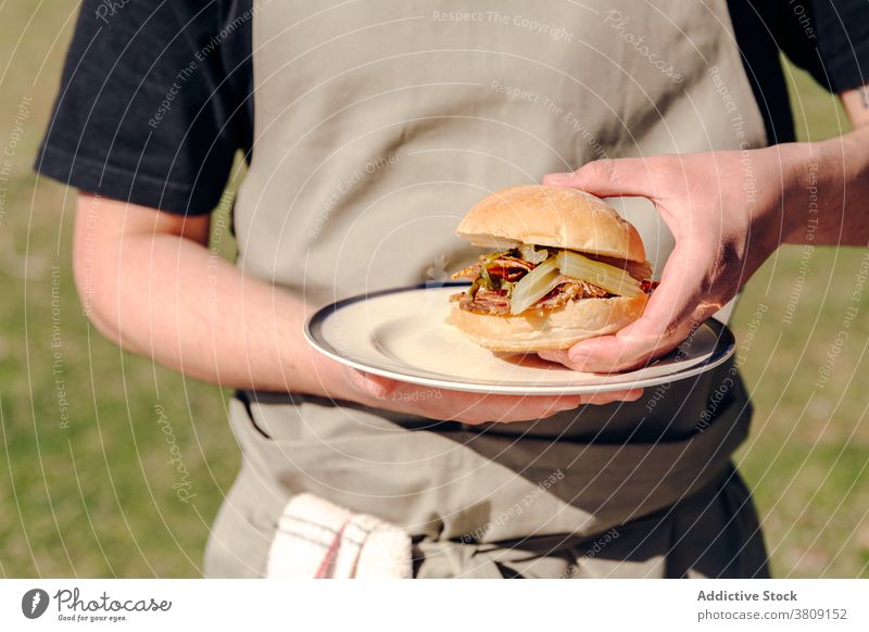 Kropfenmann mit selbstgemachtem Burger im Dorf Brötchen Koch Mann lecker Landschaft rustikal geschmackvoll Gemüse männlich dienen Schürze Teller appetitlich