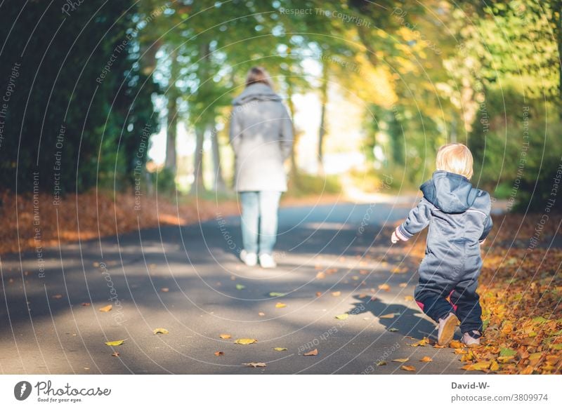 Mutter und Kind beim Spaziergang im Herbst herbstlich Laub spazieren Wald Blätter