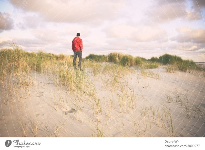 Ein Mann steht einsam in den Dünen und genießt die Stille Urlauber Ruhe Abstand stehen Meer Strand Natur Ferien & Urlaub & Reisen