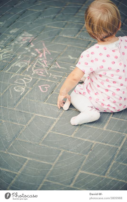 Kind malt mit Kreide auf dem Boden malen kreativität Mädchen Straßenmalkreide beschäftigung Kindheit Spaß