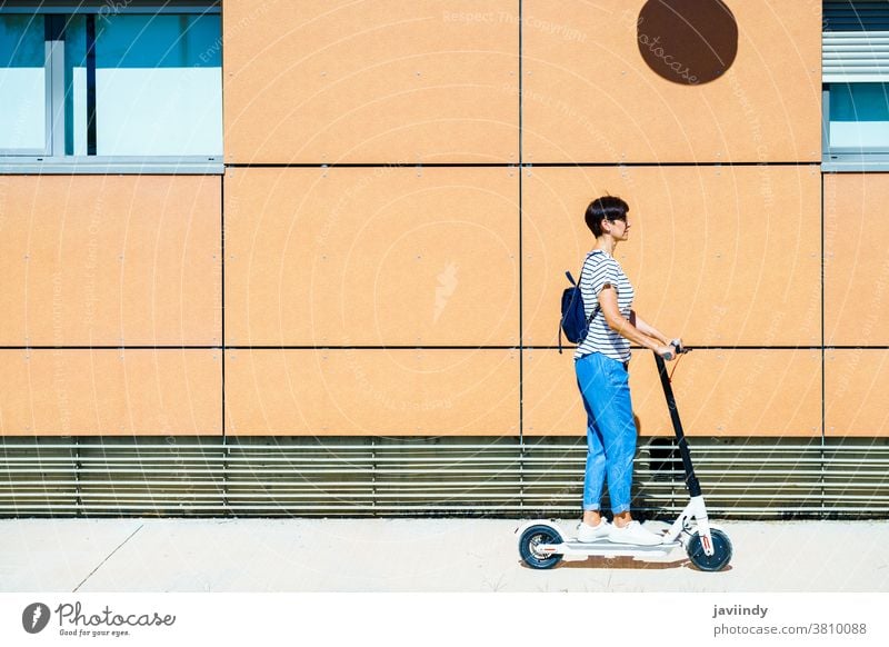 Frau fährt auf einem Elektroroller durch die Stadt Tretroller elektrisch Mädchen Öko Transport urban Lifestyle modern Freizeit Großstadt Mitfahrgelegenheit