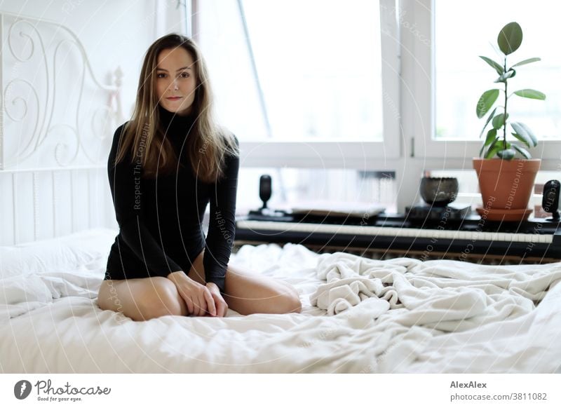 Nahes Portrait einer jungen Frau die auf einem Bett kniet und in die Kamera schaut 18-30 Jahre schön fit schlank schlau freundlich angenehm attraktiv brünett