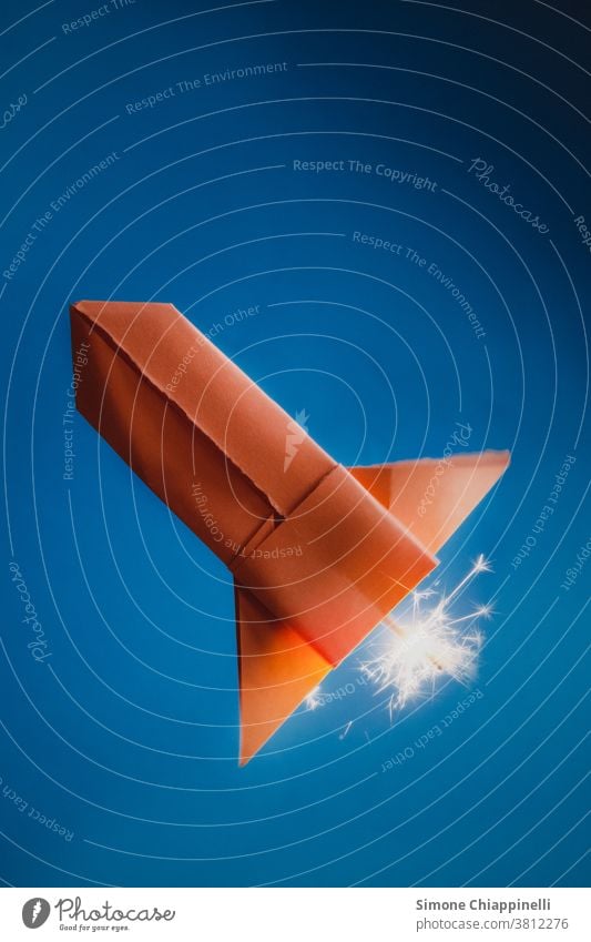 Orangefarbene Origami-Papierrakete auf blauem Hintergrund orange Rakete Weltraumrakete Himmel Farbfoto Basteln Kreativität Freizeit & Hobby Innenaufnahme