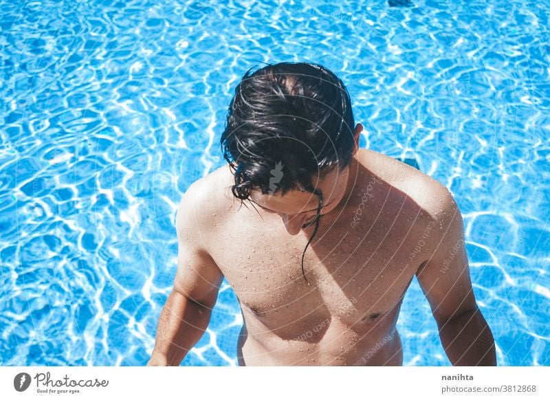 Junger, gutaussehender Mann posiert in der Nähe eines Pools attraktiv sexy männlich Schwimmbad Sommer Haut Vollbart Typ Lächeln Bräune blau Wasser Party Porträt