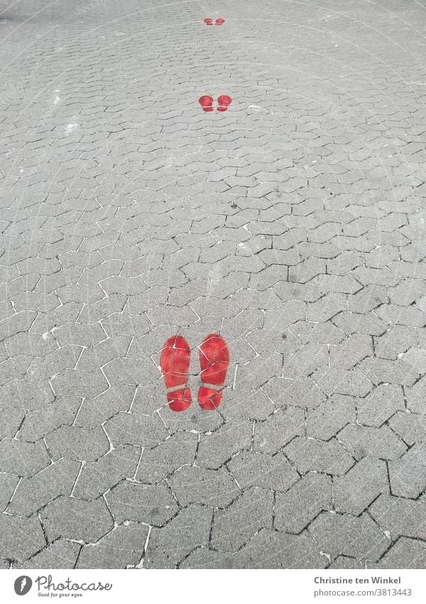 Abstand halten...  rote Fußabdrücke auf grauen Pflastersteinen | corona thoughts Mindestabstand Coronavirus Warnfarbe Pandemie Infektionsgefahr Corona-Virus