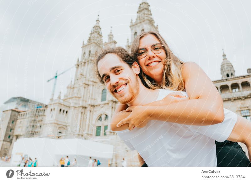 Junges Paar lächelt mit der Frau über den Mann vor einem touristischen Ort in die Kamera lässig freudig Ausflug im Freien Tourismus Ferien Erwachsene Menschen
