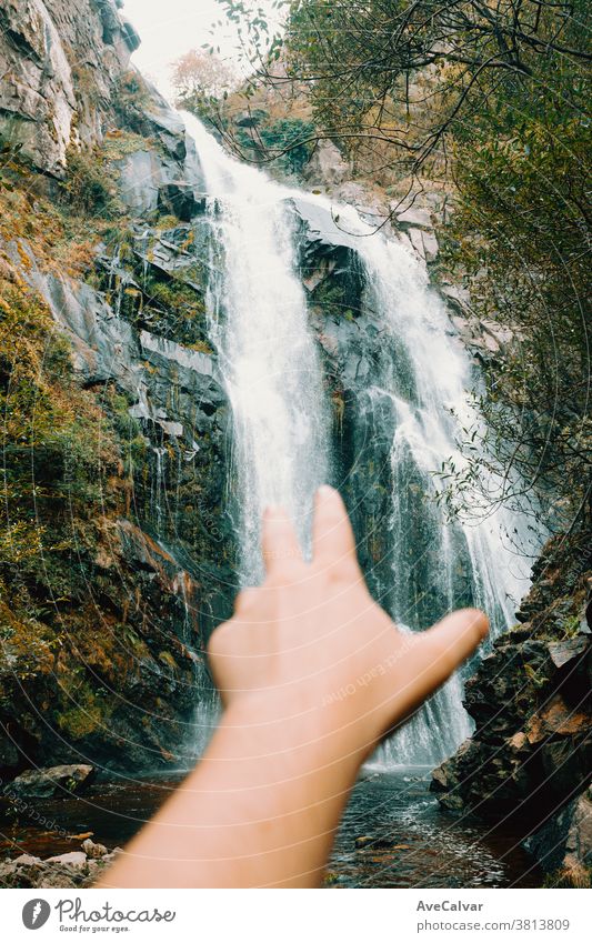 Unscharfe Hand, die zu einem majestätischen Wasserfall greift Natur Baum Western Gelassenheit Landschaft natürlich friedlich Laubwerk fallen Kaskade Wald