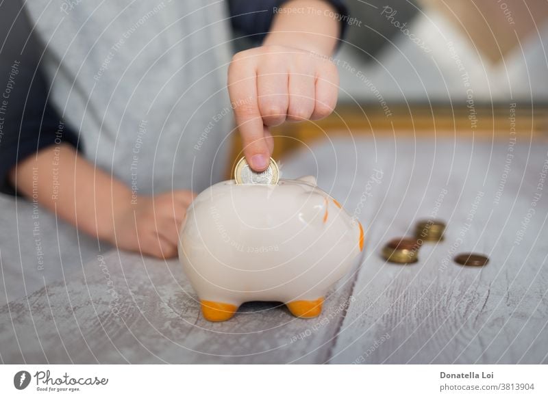 Kind wirft eine Münze ins Sparschwein zu Hause Banking Haushaltsplan Bargeld Kaukasier Keramik Kindheit Geldmünzen Münzen Konzept Krise Schulden Pfand einnehmen
