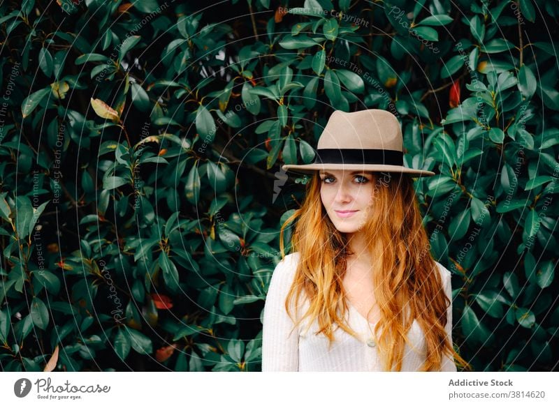 Junge Frau mit Hut im Garten stehend Stil Rotschopf trendy rote Haare modern Ingwer Mode jung lange Haare Dame selbstbewusst charmant Lifestyle elegant